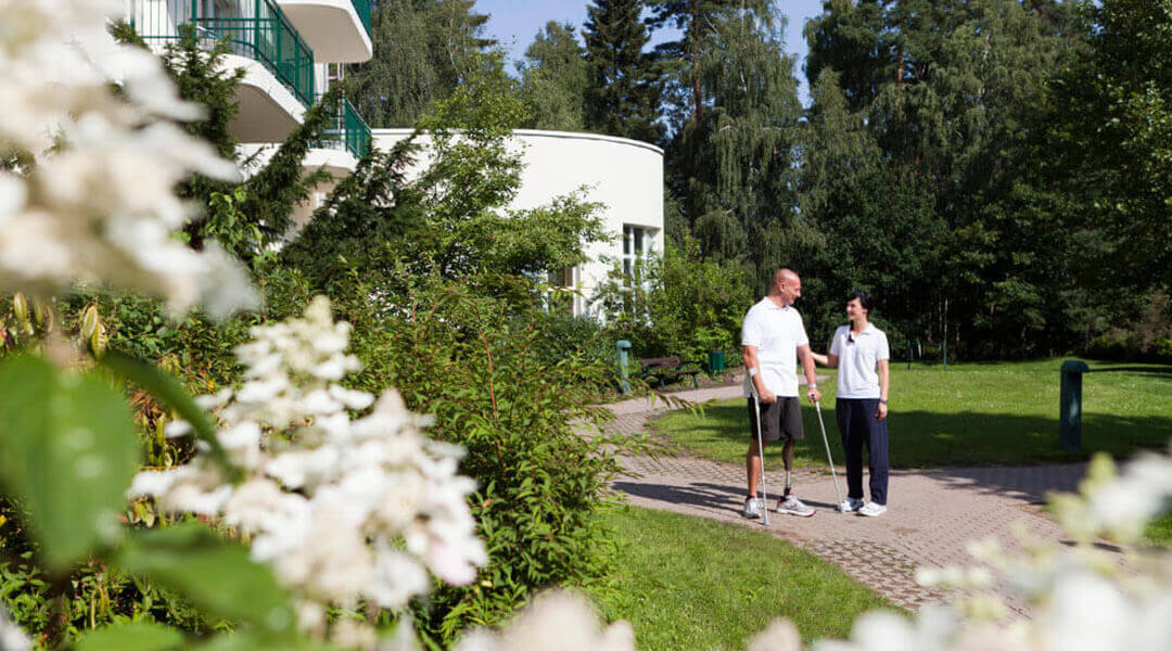 Mann mit amputiertem Bein im Gespräch vor der Klinik